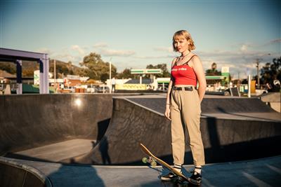 Girl standing on side of skate bowl with skate board