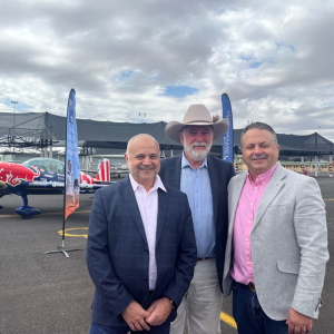 Image of three men standing together in front of a Red Bull decorated plane